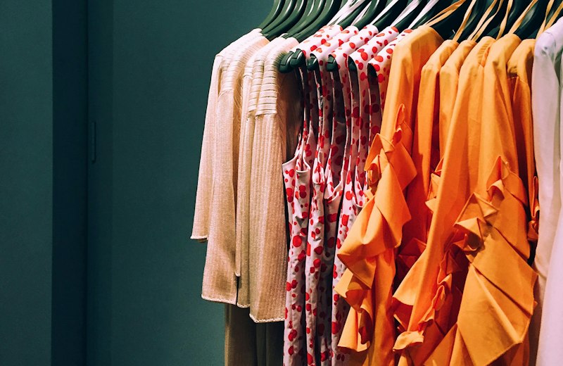 Colorful blouses and dresses hanging on a clothing rail
